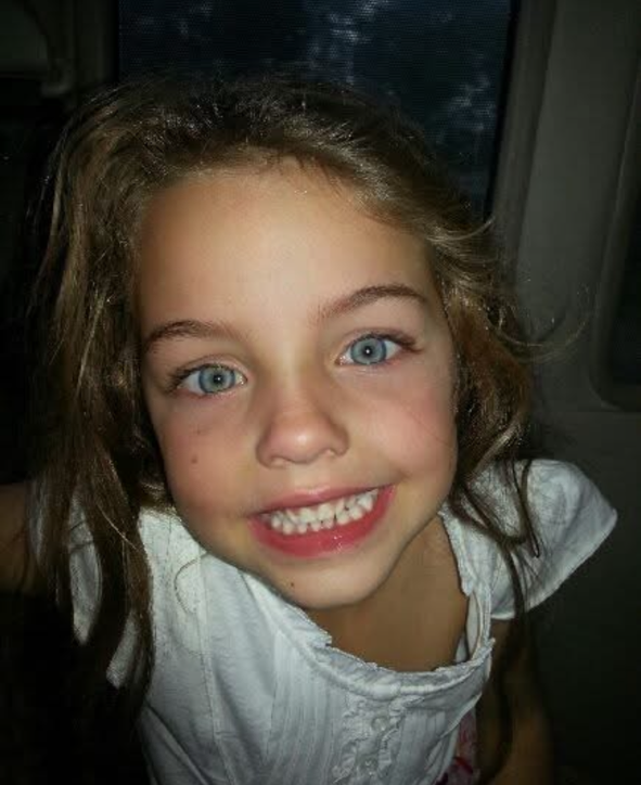 Young girl with a big smile in front of a window